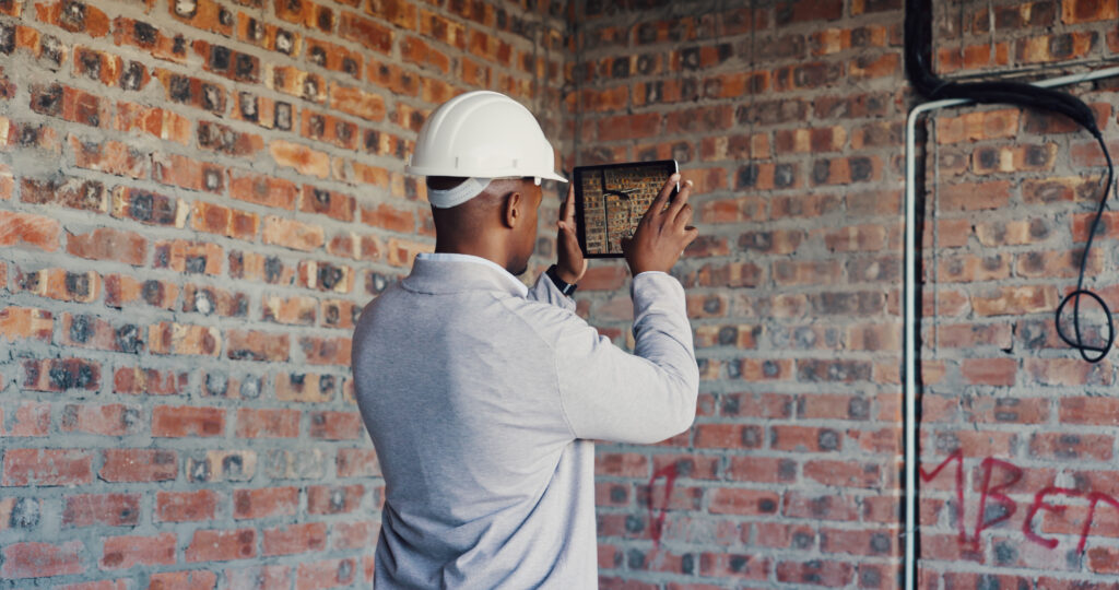 Engineer surveying a brick building with a tablet